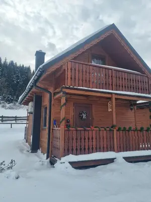 a log cabin in the snow with a porch at Domki na Zagroniu in Koninki