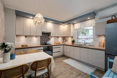 a kitchen with white cabinets and a table and chairs at Przystanek Leśna-3 Apartamenty nad potokiem w sercu natury in Targanice