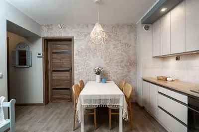a kitchen with a table with chairs and a chandelier at Przystanek Leśna-3 Apartamenty nad potokiem w sercu natury in Targanice