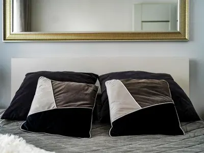 a bed with black and white pillows and a mirror at Jack II Apartment in Kraków