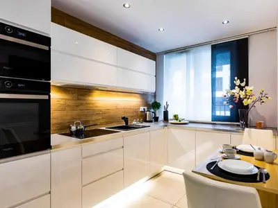 a kitchen with white cabinets and a table at Jack II Apartment in Kraków