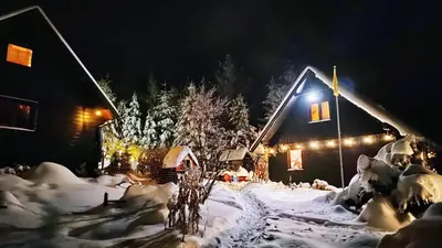 a house covered in snow at night with lights at Beskidzka Ostoja in Koszarawa