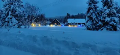 a house in the snow at night with lights at Beskidzka Ostoja in Koszarawa