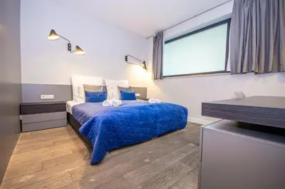 a bedroom with a bed with blue sheets and a window at InPoint Executive Apartments near Old Town & Kazimierz District in Kraków