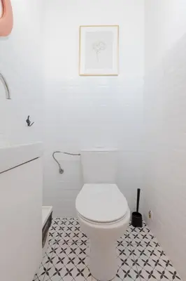 a bathroom with a white toilet and a black and white tile floor at Prime Location Apartment in Kraków