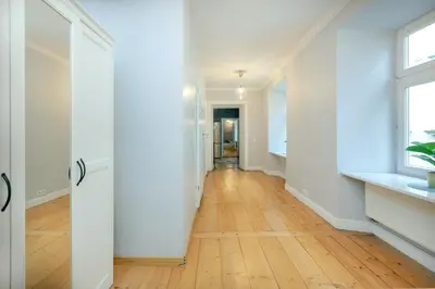 an empty hallway with white walls and a hard wood floor at Prime Location Apartment in Kraków