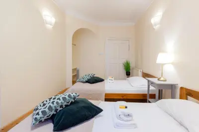 a bedroom with two beds and a table with a lamp at Prime Location Apartment in Kraków