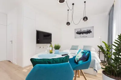 a white living room with blue chairs and a table at City of the Kings - Smile Apartment in Kraków