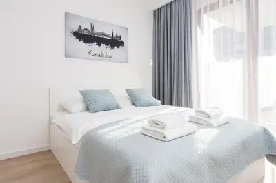 a white bedroom with a bed with towels on it at City of the Kings - Smile Apartment in Kraków
