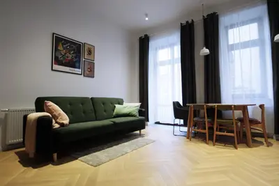 a living room with a green couch and a table at Apartament LIMANO in Kraków