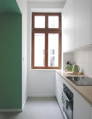 a kitchen with white cabinets and a window at Apartament LIMANO in Kraków