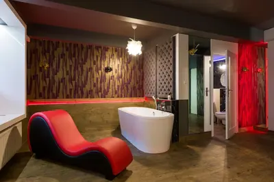 a bathroom with a white tub and a red chair at Yourplace Romantic Apartment with private patio in Kraków