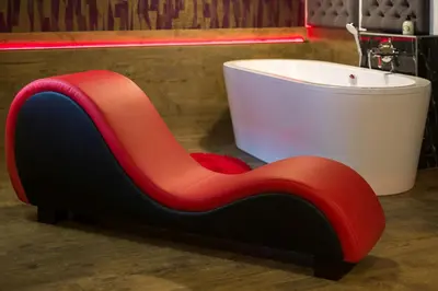 a red and black chair next to a bath tub at Yourplace Romantic Apartment with private patio in Kraków