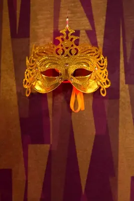 a gold mask with a red bow on a table at Yourplace Romantic Apartment with private patio in Kraków