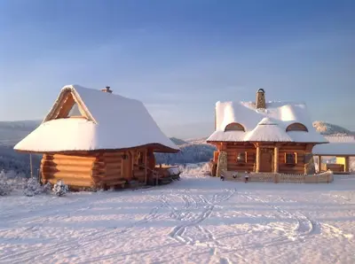 two wooden cabins with snow covered roofs in the snow at Osada Beskidzka in Zawoja