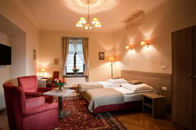 a hotel room with two beds and a chair at Hotel Santi in Kraków