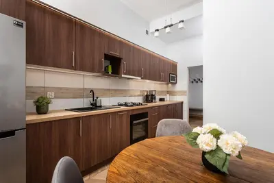 a kitchen with wooden cabinets and a table with flowers at Classy Old Town Apartment - by Upstairs in Kraków