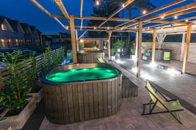 a hot tub on a patio with a table and a chair at Old Tree Villa & Restaurant in Oświęcim