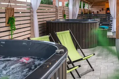 a hot tub and two lawn chairs in a backyard at Old Tree Villa & Restaurant in Oświęcim