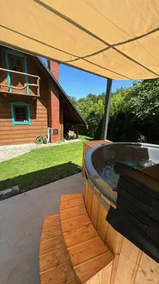 a hot tub under an umbrella on a patio at Domek pod Jaworami z balią in Sułkowice