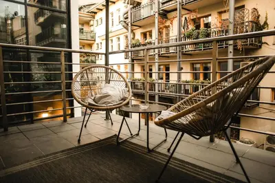a balcony with two chairs and a table and a building at Vilao Apartments in Kraków