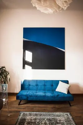 a blue couch in a living room with a painting at Vilao Apartments in Kraków