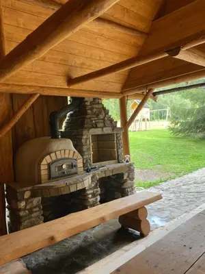 a stone oven sitting under a wooden roof at Domek na Cepcowym in Obidowa