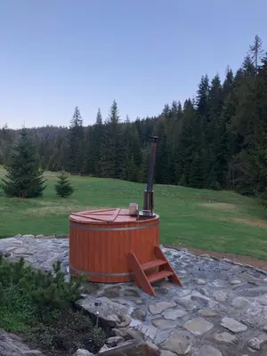 a wooden hot tub sitting on a stone ground at Domek na Cepcowym in Obidowa