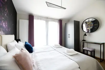 a bedroom with a large white bed with a clock on the wall at Aparthotel Inspire Miodova Residence in Kraków