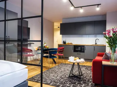 a living room and kitchen with a red couch and a table at Aparthotel Inspire Miodova Residence in Kraków