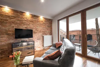 a living room with a couch and a brick wall at Rakowicka Top Apartaments Superior in Kraków