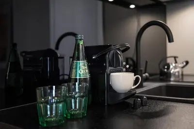 a bottle of beer and two glasses on a kitchen counter at Rakowicka Top Apartaments Superior in Kraków