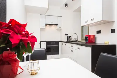 a kitchen with a table with a vase with red flowers at InPoint Krupnicza Apartment - 5 minut from Main Square Self Check-in in Kraków