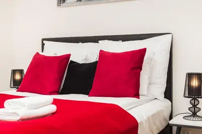 a red and white bed with red pillows at InPoint Krupnicza Apartment - 5 minut from Main Square Self Check-in in Kraków