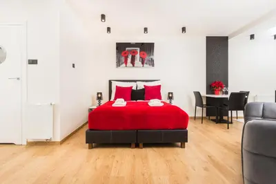a bedroom with a red bed and a dining room at InPoint Krupnicza Apartment - 5 minut from Main Square Self Check-in in Kraków