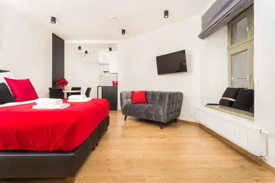 a bedroom with a red bed and a chair at InPoint Krupnicza Apartment - 5 minut from Main Square Self Check-in in Kraków
