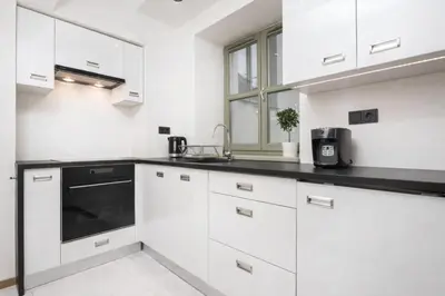 a kitchen with white cabinets and a black counter top at InPoint Krupnicza Apartment - 5 minut from Main Square Self Check-in in Kraków