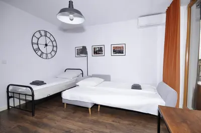 two beds in a room with a clock on the wall at Schindler’s Factory Zabłocie Deluxe Apartments WAWELOFTS in Kraków