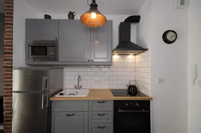 a kitchen with a sink and a refrigerator at Schindler’s Factory Zabłocie Deluxe Apartments WAWELOFTS in Kraków