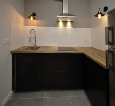 a kitchen with black cabinets and a sink at Schindler’s Factory Zabłocie Deluxe Apartments WAWELOFTS in Kraków
