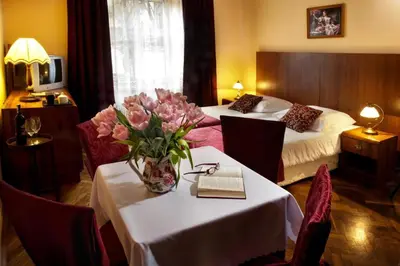 a hotel room with two beds and a table with flowers at Red Carpet Premium in Kraków