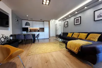 a living room with a black couch and a kitchen at Duplex apartment Morsztynowska in Kraków