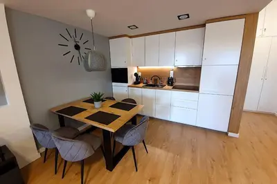 a kitchen with a table and chairs and a clock on the wall at Duplex apartment Morsztynowska in Kraków