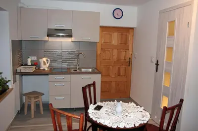 a room with a table and a kitchen with a door at Apartament U Jacka 2 in Rabka