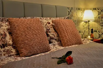 a bed with two pillows and a red flower on it at Cracovia Garden Nowa 5 Dzielnica in Kraków