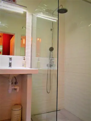 a shower with a glass door next to a sink at Cracovia Garden Nowa 5 Dzielnica in Kraków