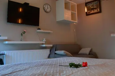 a bedroom with a bed and a couch and a clock at Cracovia Garden Nowa 5 Dzielnica in Kraków