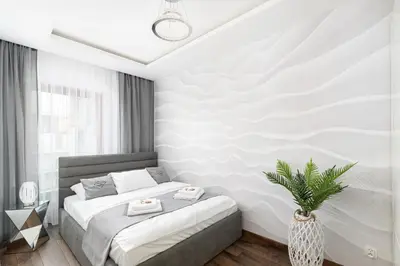 a white bedroom with a bed and a plant at Crystal Luxury Apartments Rakowicka 20H in Kraków