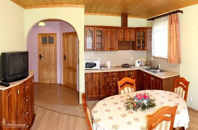 a kitchen with a table and a dining room with a tv at Willa Modrysówka in Zawoja