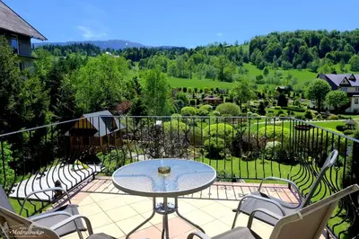 a patio with a table and chairs on a balcony at Willa Modrysówka in Zawoja